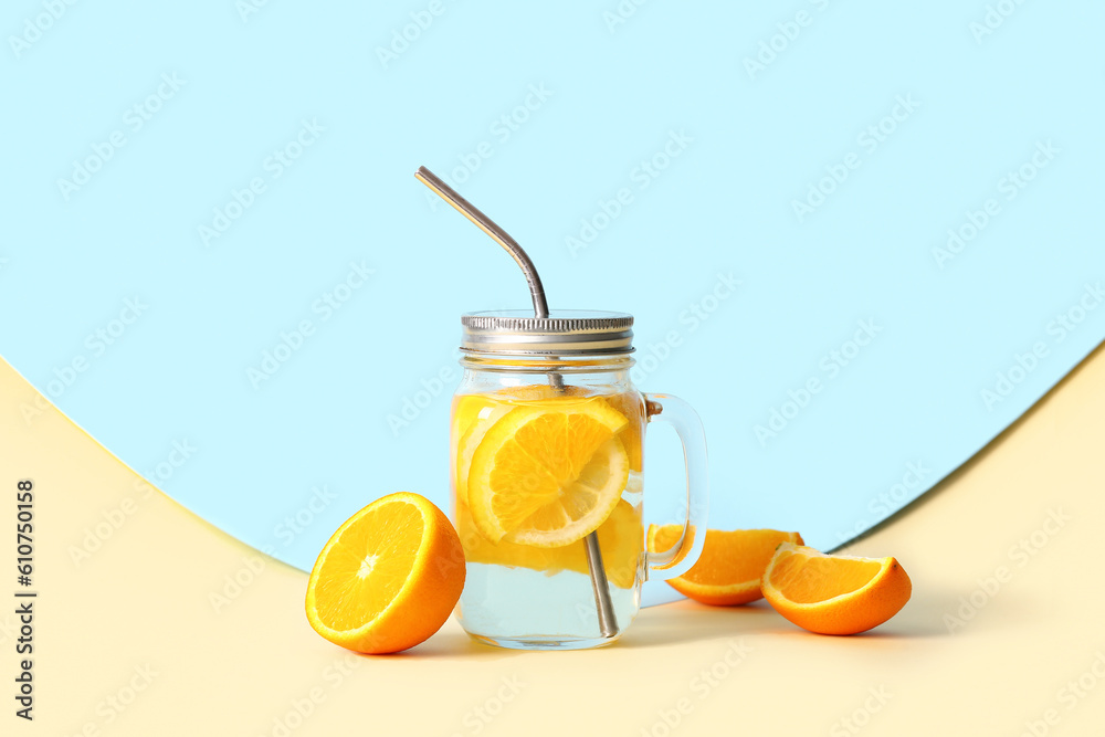 Mason jar of infused water with orange slices on colorful background