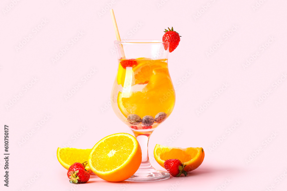 Glass of infused water with orange slices on pink background