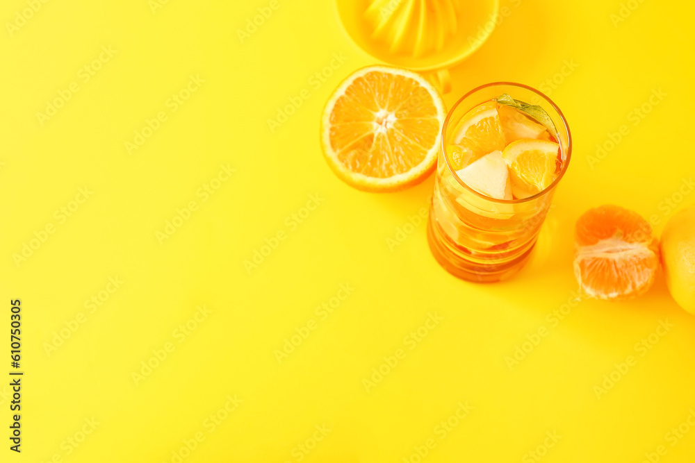 Glass of infused water with different sliced fruits on yellow background