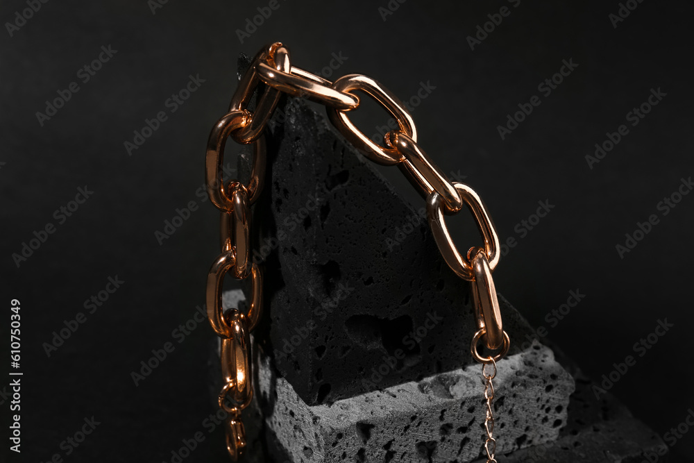 Decorative podium with beautiful chain bracelet on black background