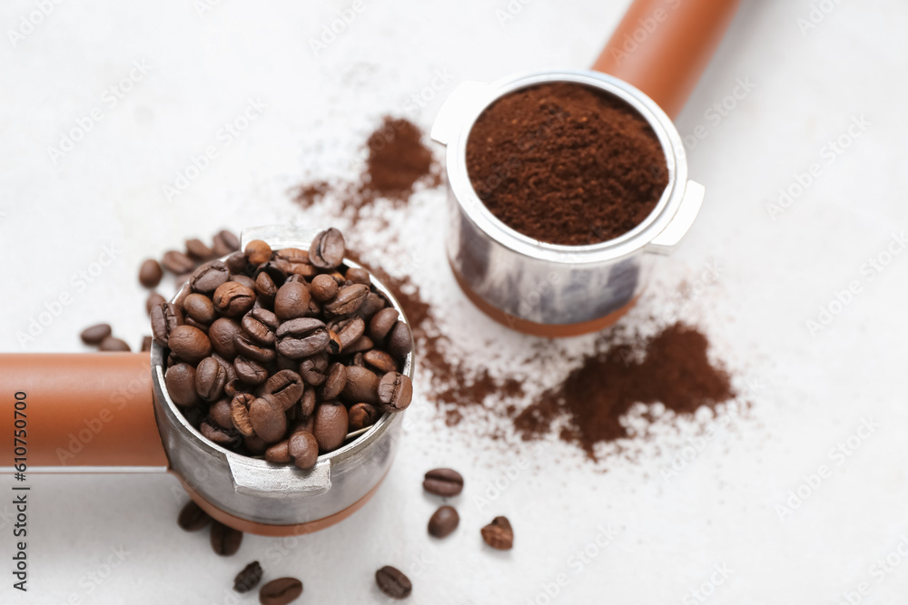 Portafilters with coffee beans and powder on light background