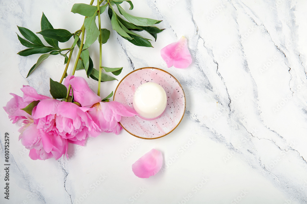 Plate of panna cotta with beautiful peony flowers on white table