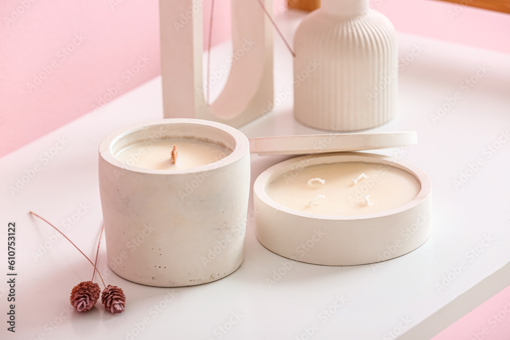 Holders with candles and decor on table in room, closeup