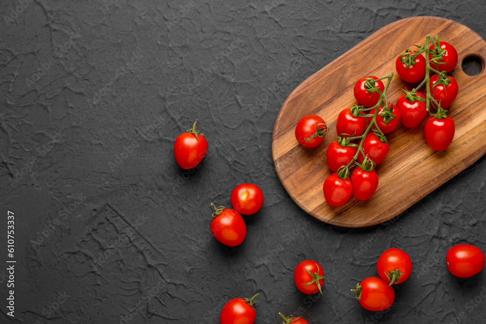 Wooden board with fresh cherry tomatoes on black background