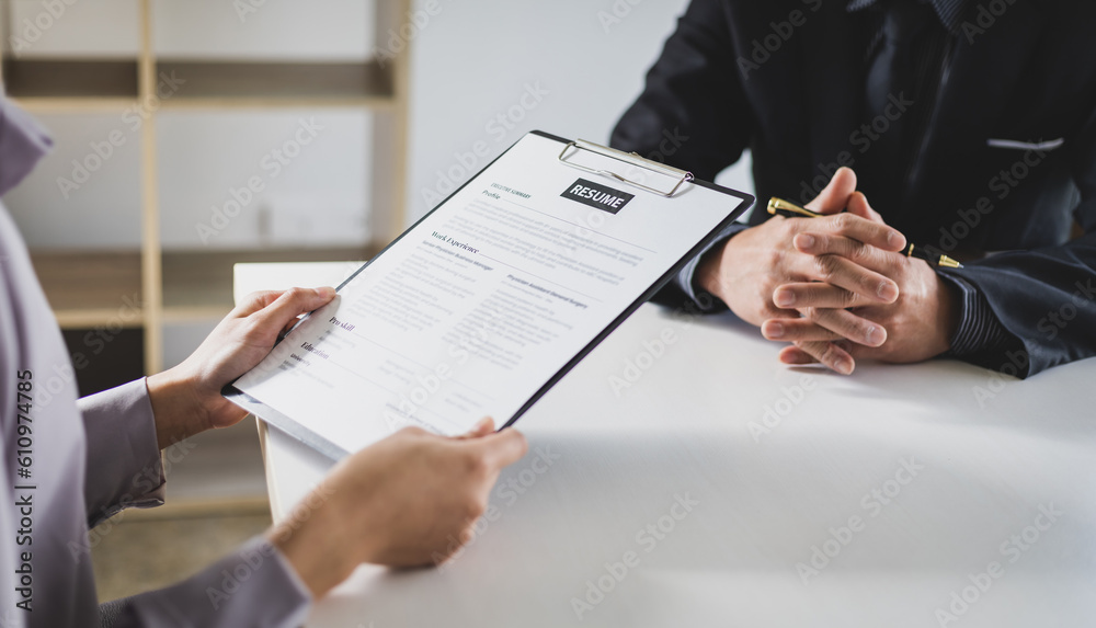 Woman submits an application to the personnel committee. The manager reads the resume and discusses 