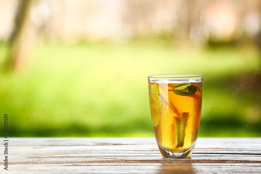 Glass of tasty cold ice tea on table outdoors