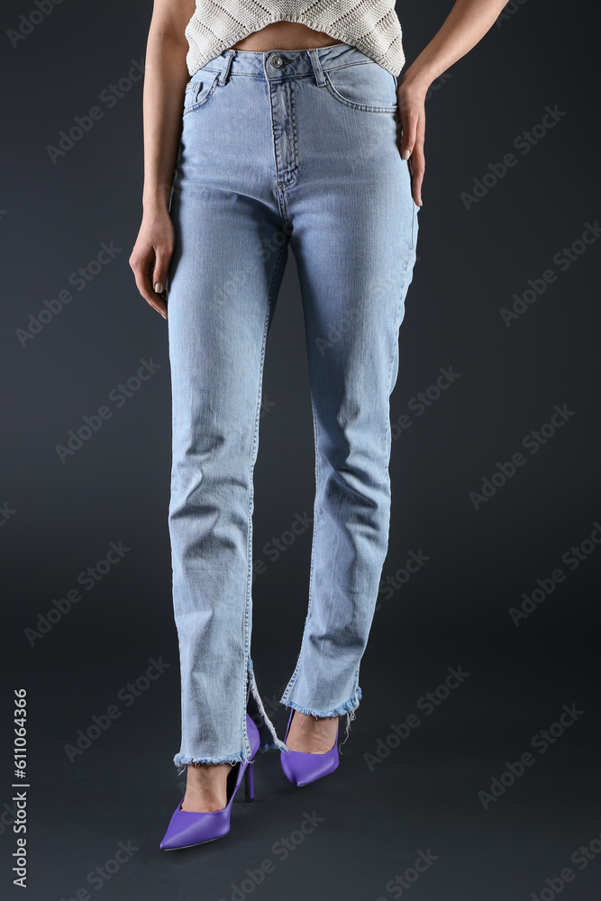 Young woman in stylish jeans on dark background