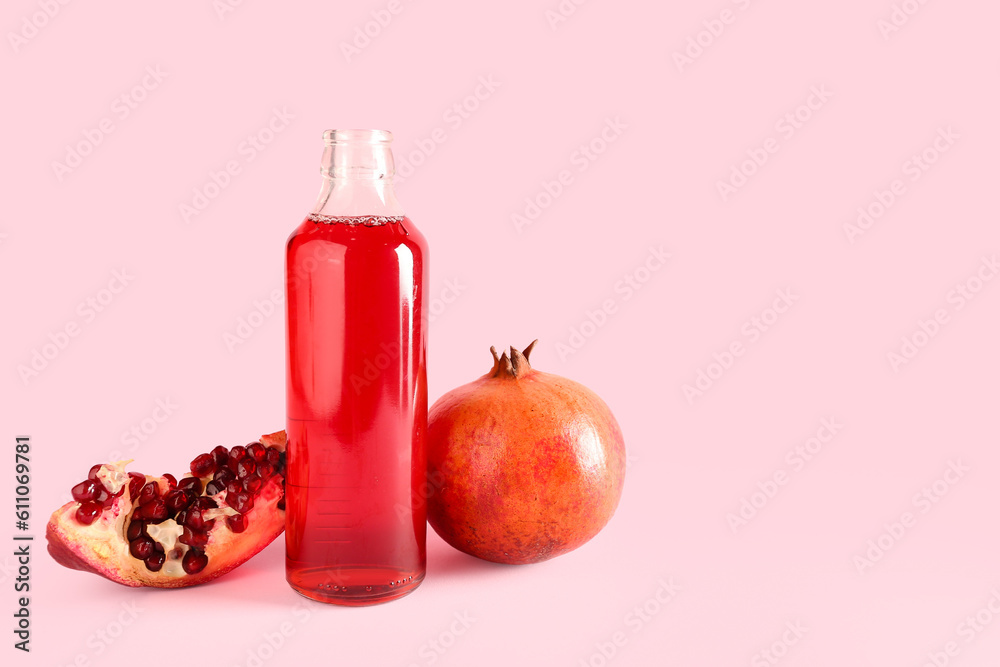 Bottle of fresh pomegranate juice on pink background