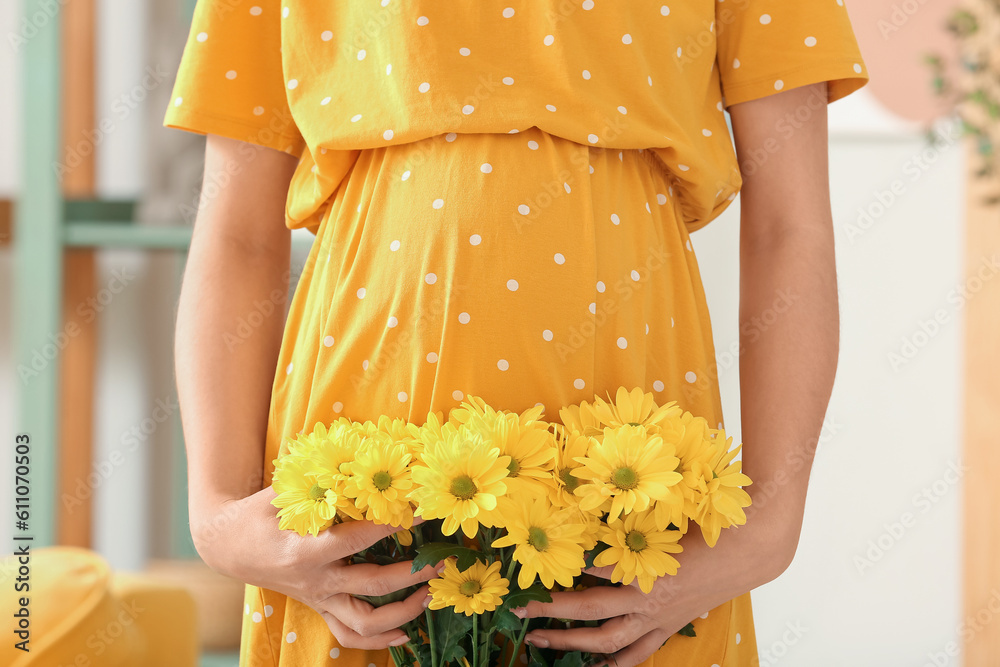 Young pregnant woman with chrysanthemum flowers at home, closeup