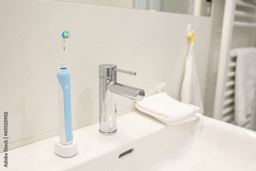 Electric toothbrush on white sink in bathroom