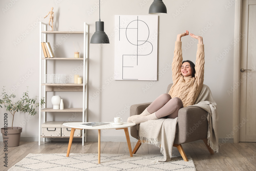 Young woman sitting in soft armchair at home