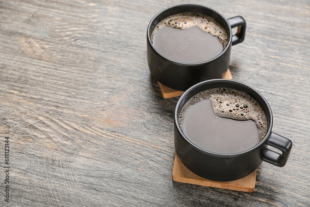 Drink coasters with cups of coffee on wooden table