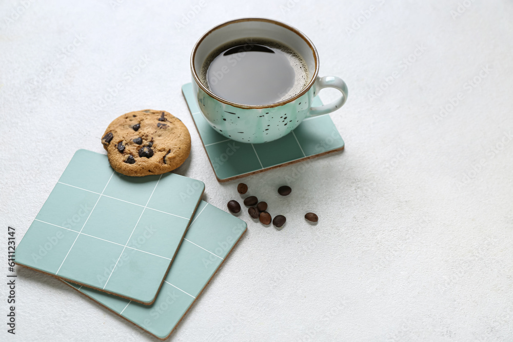 Drink coasters with cup of coffee, cookie and beans on white table