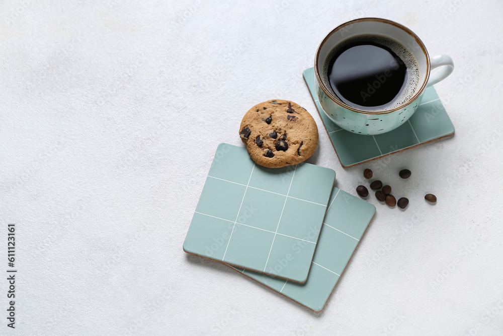 Drink coasters with cup of coffee, cookie and beans on white table