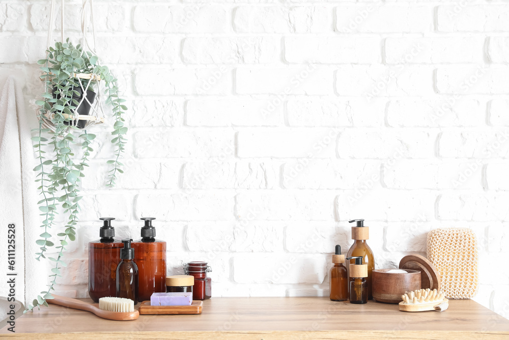 Bath accessories on table near white brick wall