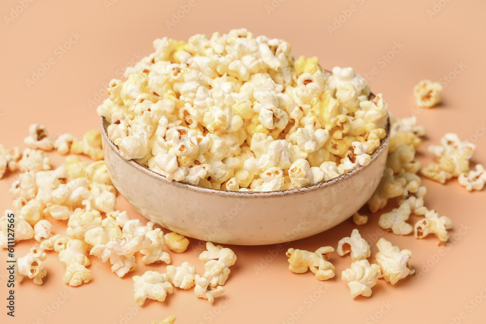 Bowl with crispy popcorn on beige background