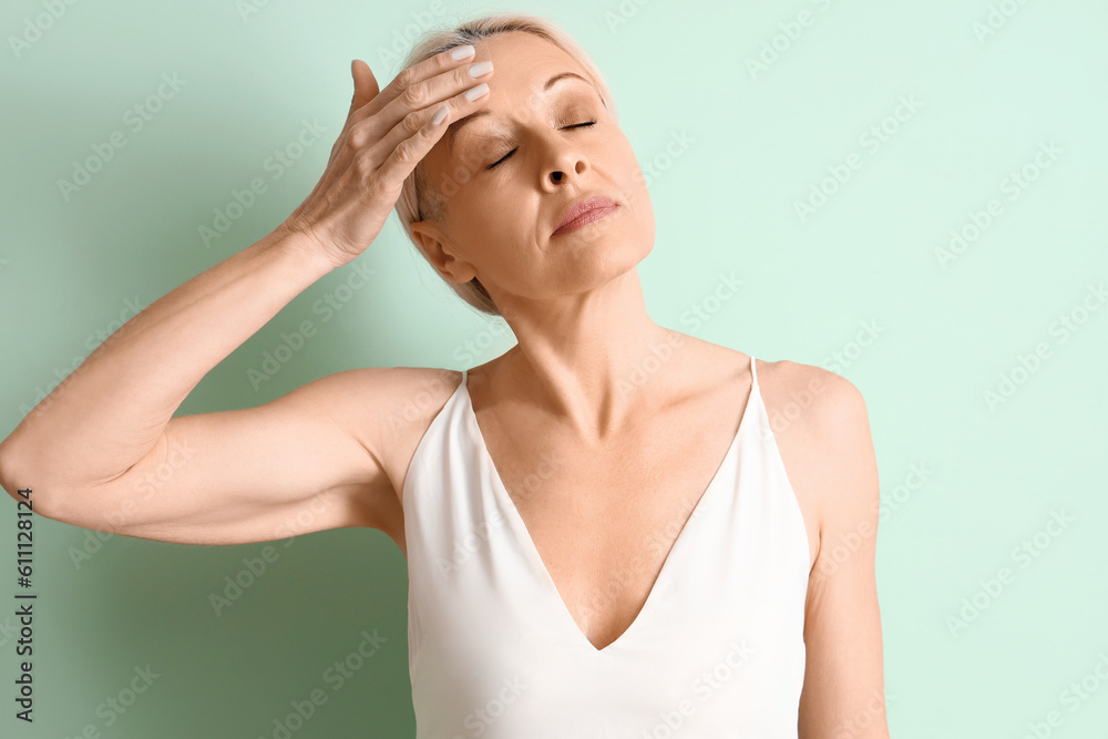 Mature woman doing face building exercise on green background