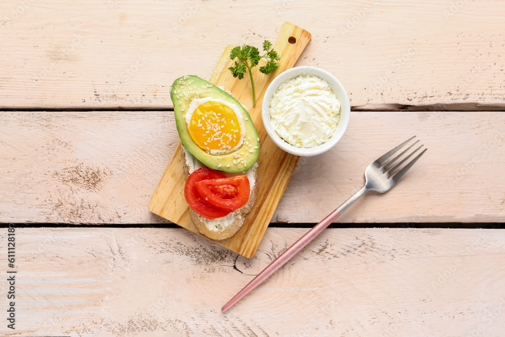 Board of tasty bruschetta with avocado and cream cheese on light wooden background