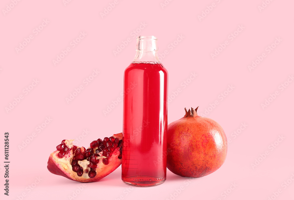 Bottle of fresh pomegranate juice on pink background