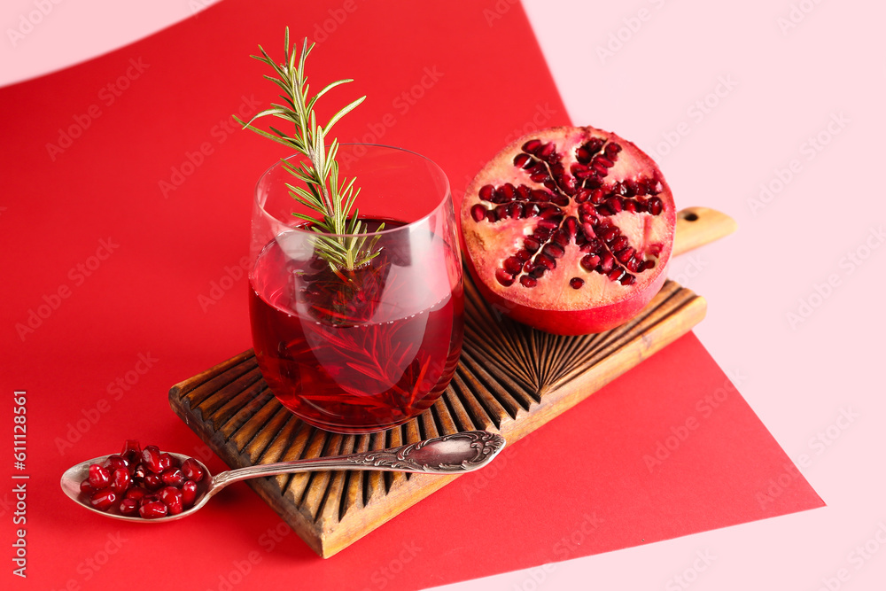 Board with glass of fresh pomegranate juice on colorful background