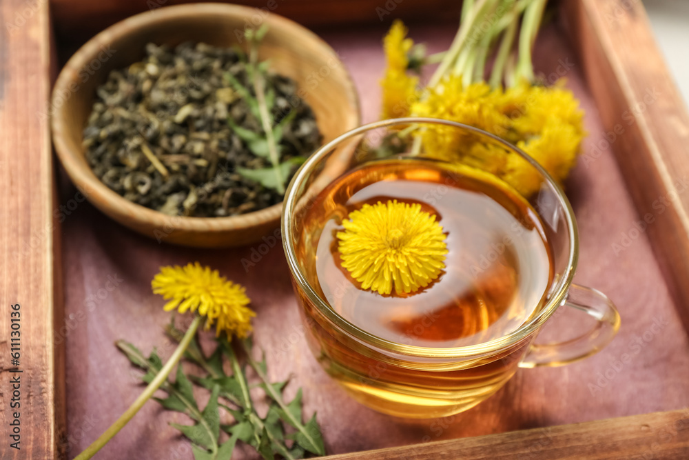 Glass cup of healthy dandelion tea on wooden board