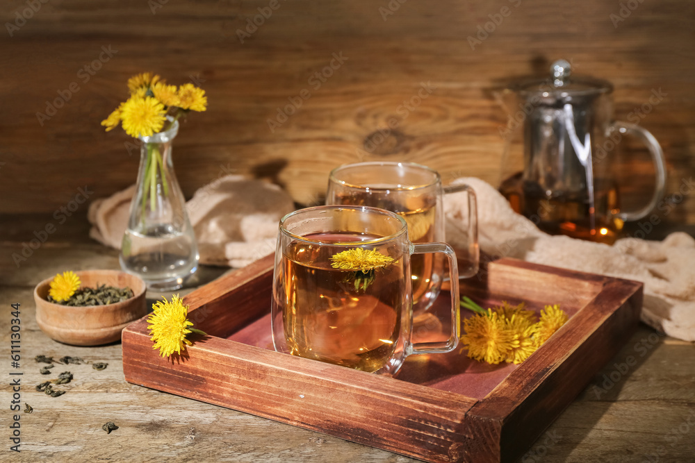 Board with glass cups of healthy dandelion tea on wooden table