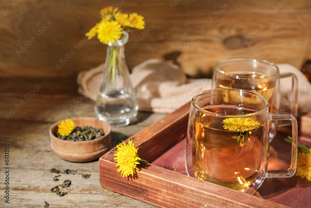 Board with glass cups of healthy dandelion tea on wooden table