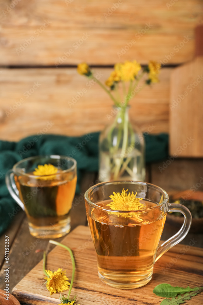 Board with glass cups of healthy dandelion tea on wooden table