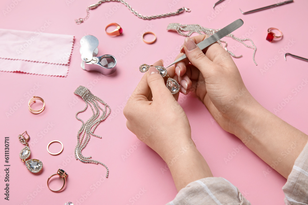 Woman cleaning beautiful earring on pink background, closeup