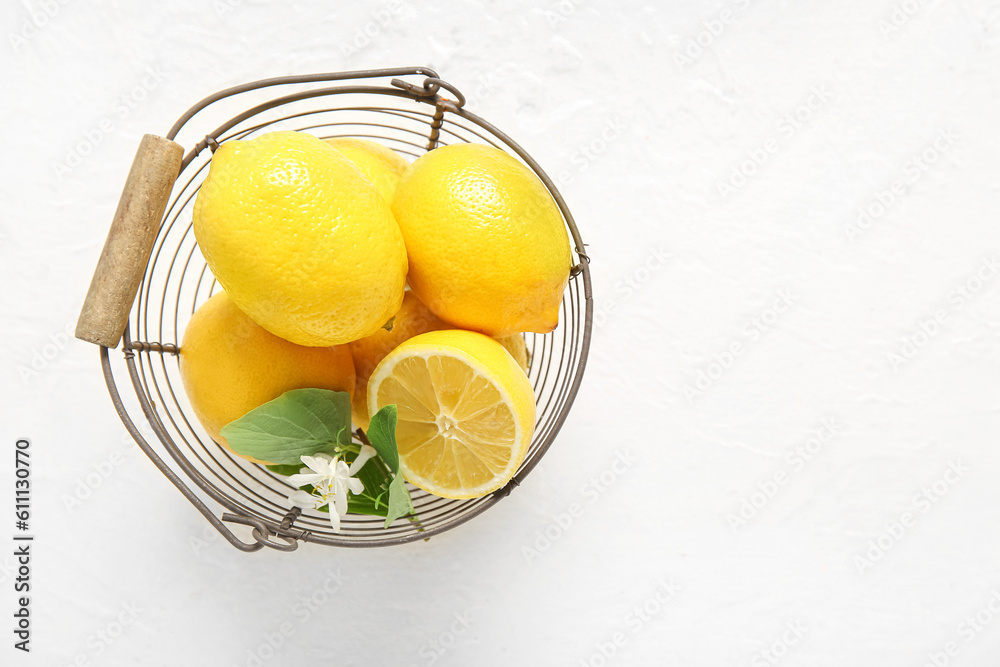 Basket of lemons with blooming branch on white table