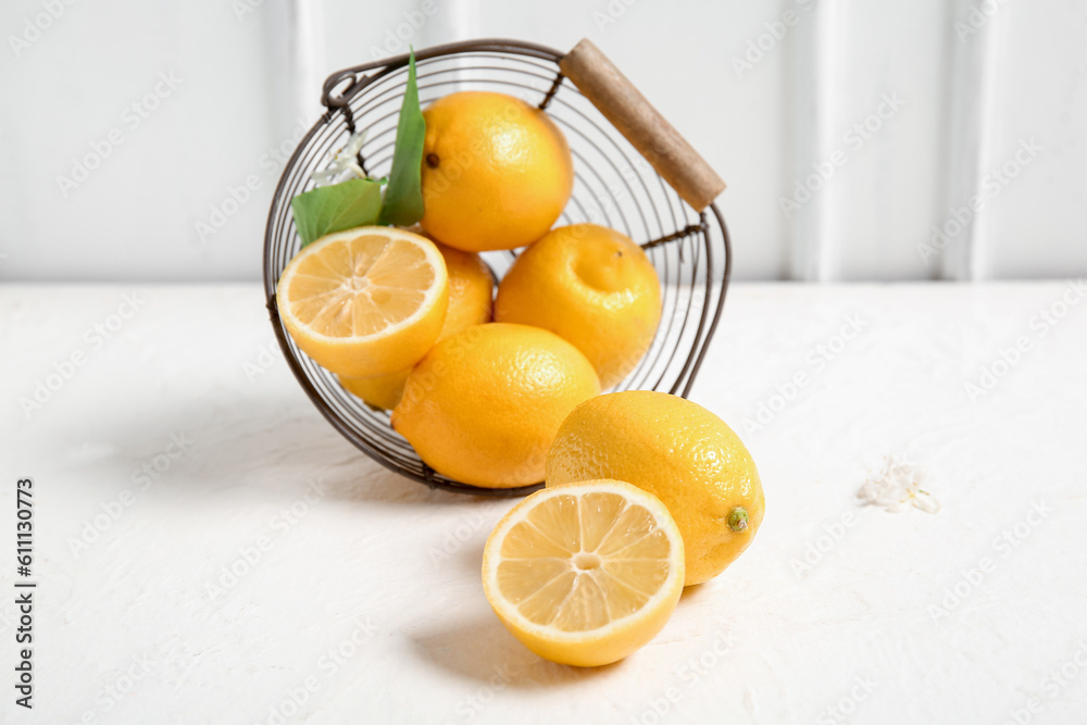 Basket of lemons with blooming branch on white table