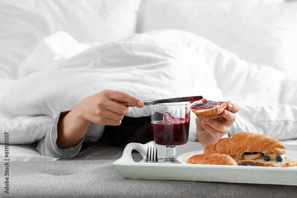 Morning of young woman having breakfast in bedroom, closeup