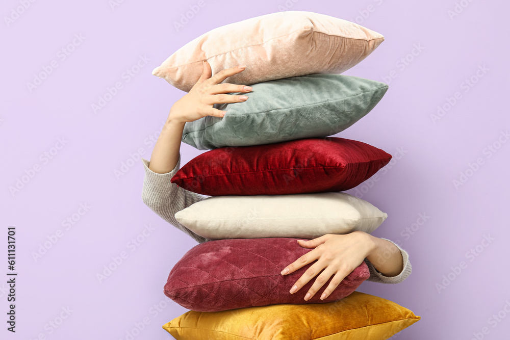 Woman with stylish pillows near lilac wall