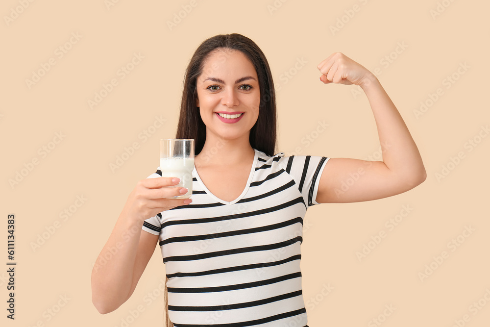 Healthy young woman with glass of milk on beige background