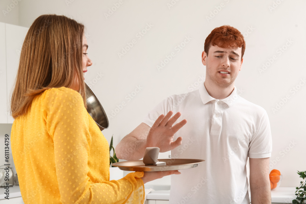 Young man rejecting marriage proposal from her girlfriend in kitchen