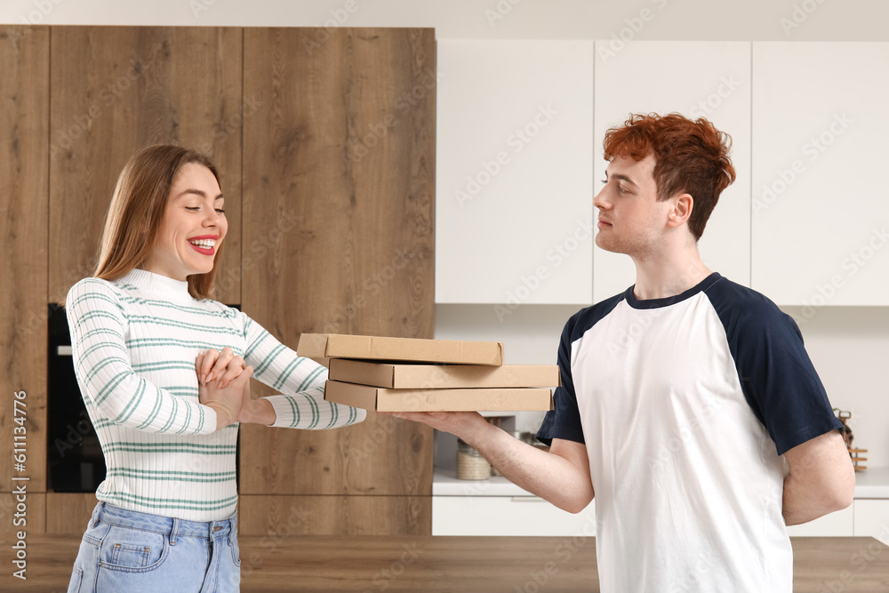 Young man with pizza proposing to his girlfriend in kitchen