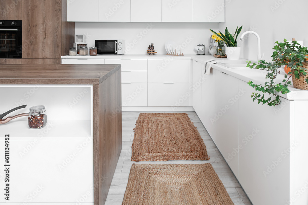 Wicker rugs on floor in interior of light kitchen