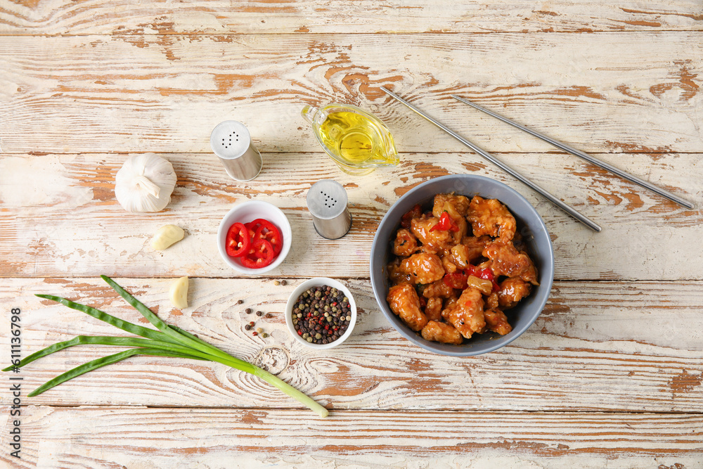 Tasty sweet and sour chicken in bowl with spices on light wooden background