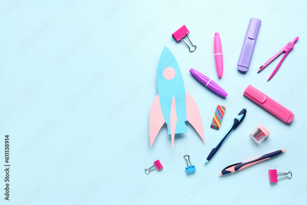 Paper rocket with different stationery on blue background