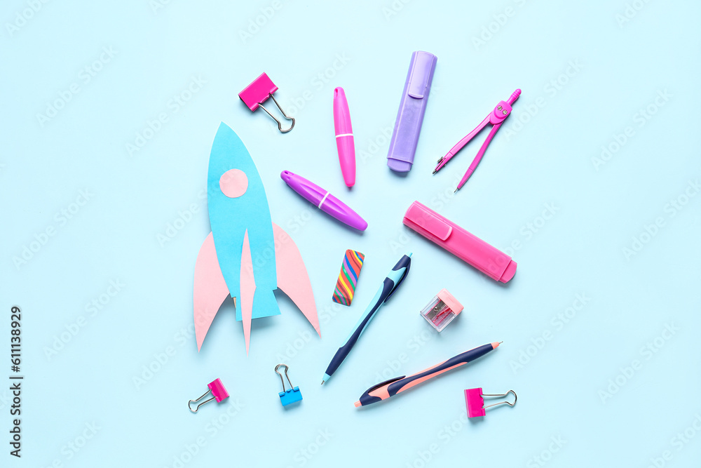 Paper rocket with different stationery on blue background