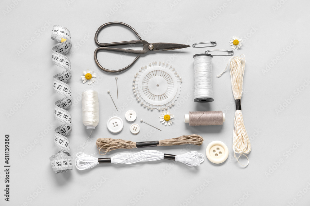 Set of different embroidery supplies on grey background