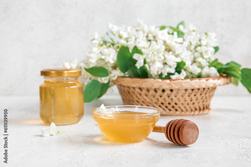 Basket with acacia flowers and sweet honey on light background