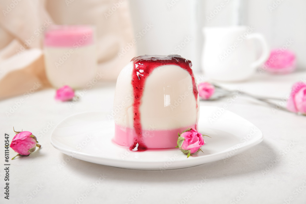 Plate of panna cotta with berry sauce and beautiful pink rose flowers on white table