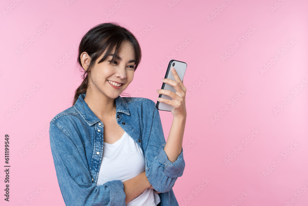 Portrait of young Asian woman using smartphone isolated studio pink background