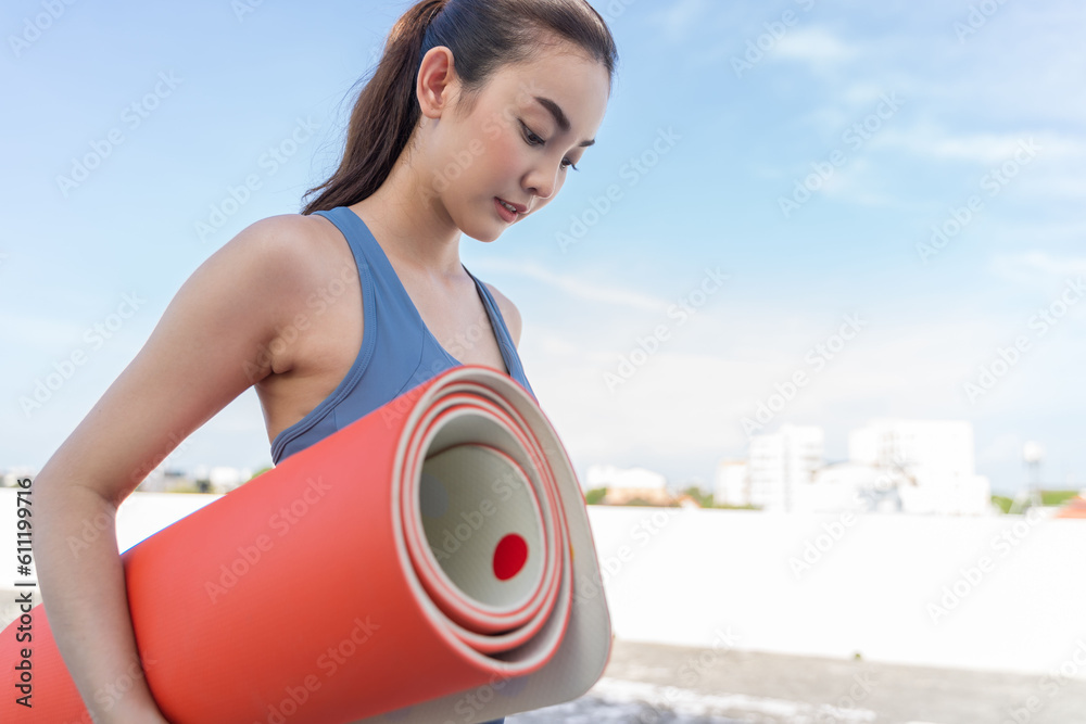 Young Asian woman picking up yoga mat after exercising.outdoor exercise fitness concept