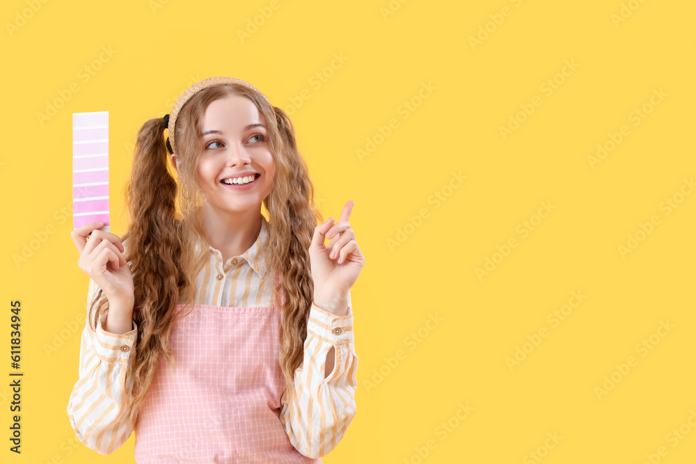 Female artist with paint color palette pointing at something on yellow background