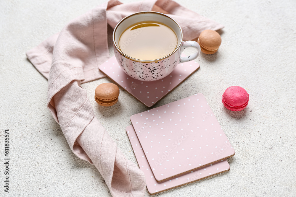 Drink coasters with cup of tea and macaroons on white table