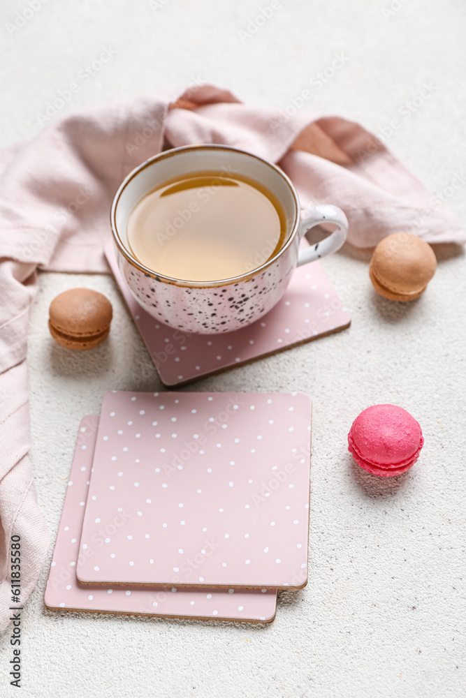 Drink coasters with cup of tea and macaroons on white table