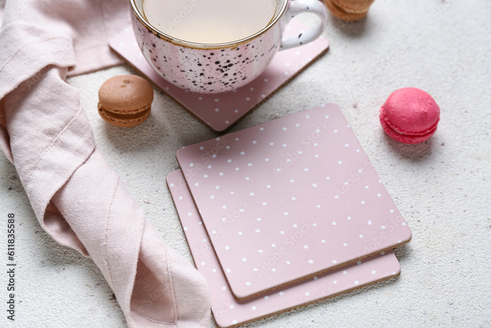 Drink coasters with cup of tea and macaroons on white table