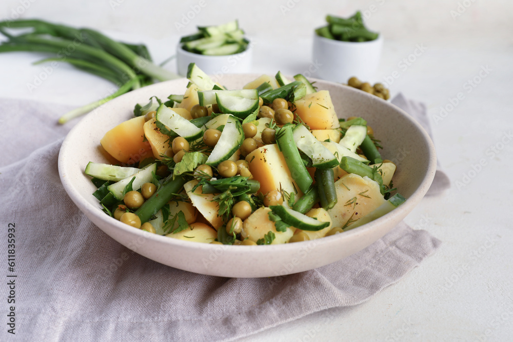 Bowl of tasty Potato Salad with vegetables on light background